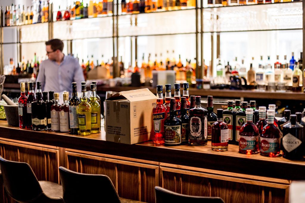 Barman achter de bar van een cafe met flessen in de rug