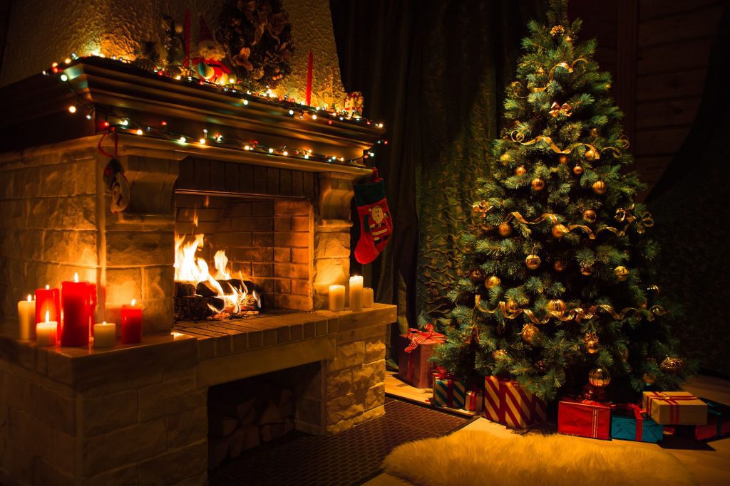 Kerstboom en brandende open haard met cadeaus eronder