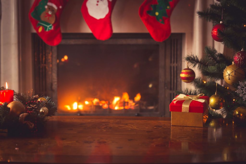 Open haard met kerstsokken, kaarsen en een cadeau