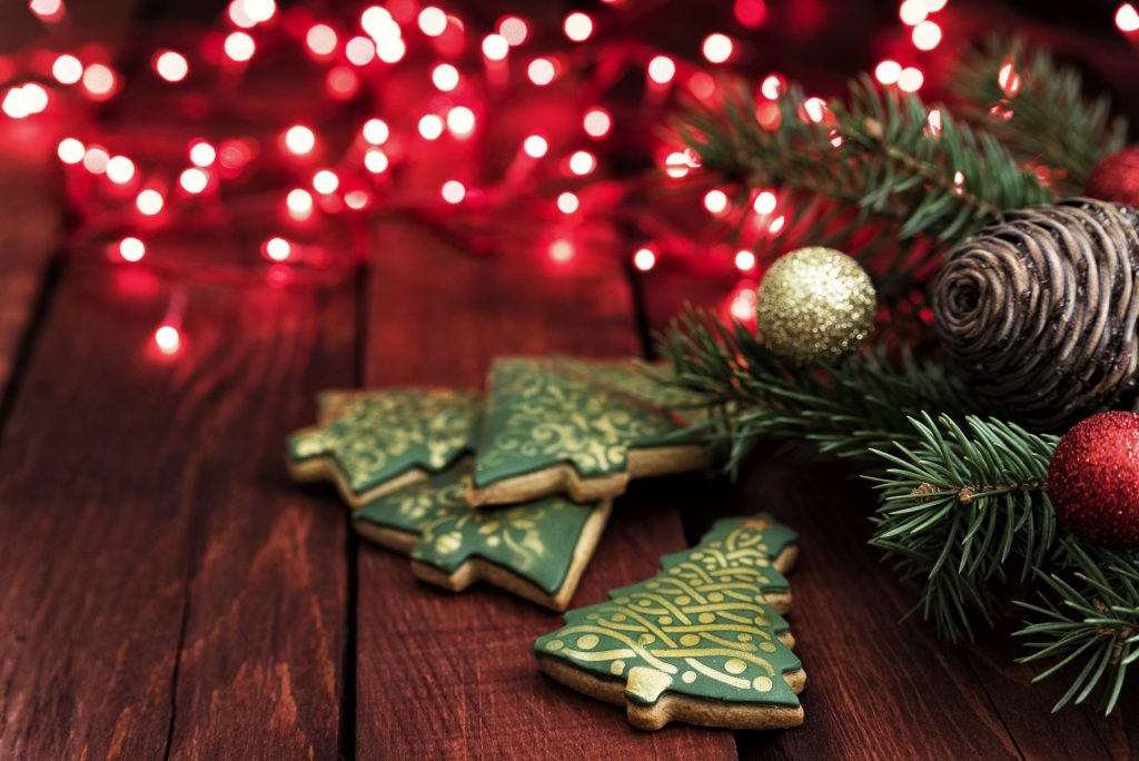 Kerstkoekjes en dennentakken op een houten tafel met lichtjes
