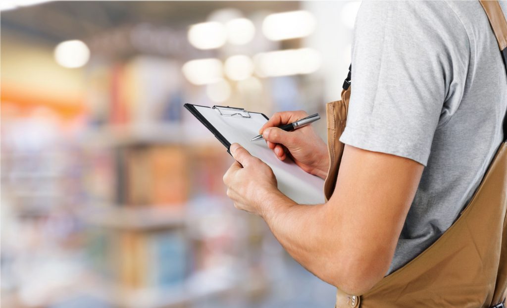 Medewerker noteert een bestelling op een klembord in het magazijn